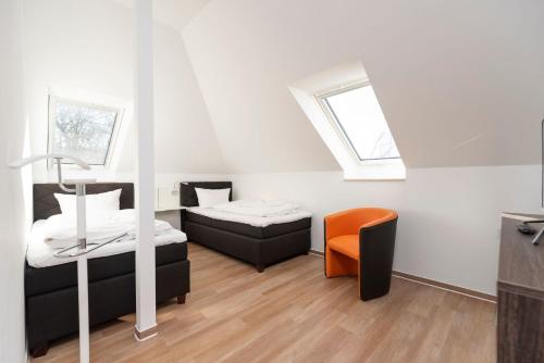 ヘリングスドルフにあるFerienwohnung 08 Villa Eviのベッド2台と椅子が備わる小さな客室です。