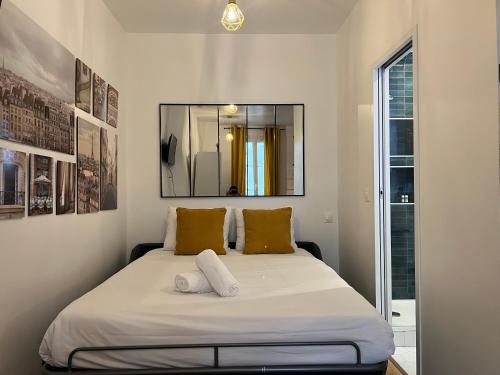 une chambre avec un lit avec deux oreillers et un miroir dans l'établissement Tour Eiffel Apartment, à Paris
