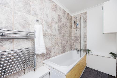 a white bathroom with a tub and a sink at Ebony Door Serviced Accommodation Barking Riverside in Barking