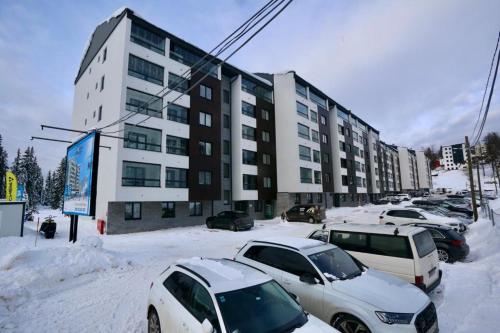 a snow covered parking lot in front of a building at Apartman Carra in Jahorina