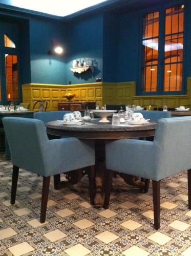 a dining room with a wooden table and blue chairs at Hôtel du Commerce in Montauban