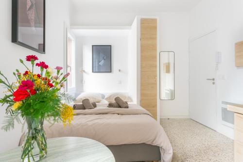 1 dormitorio con 1 cama y un jarrón de flores sobre una mesa en Charmant studio tout confort en cœur de ville en Montpellier
