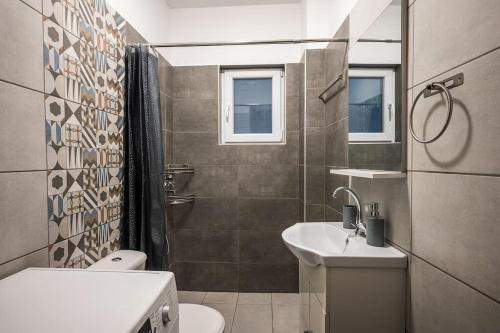 een badkamer met een wastafel, een toilet en een spiegel bij Sofman city center apartment I in Heraklion