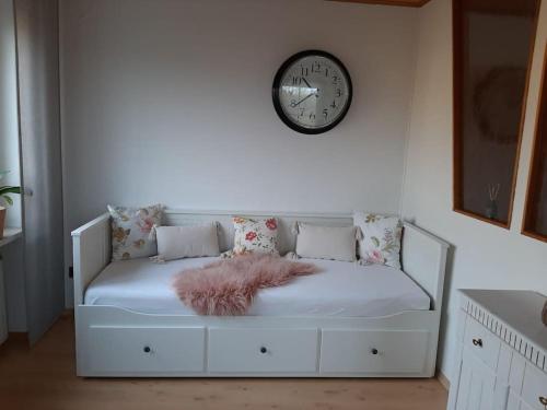a white couch with a clock on the wall at Ferienwohnung am Steinwald in Krummennaab