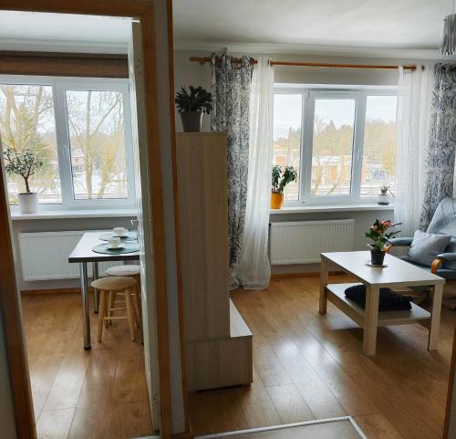 uma sala de estar com uma mesa e duas janelas em Station street apartments em Sigulda