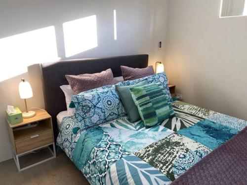uma cama com almofadas coloridas num quarto em Smart Modern Close City/Airport WIFI/Park/Netflix em Perth