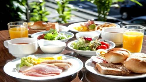 a wooden table with plates of food and glasses of orange juice at New Osaka Hotel Shinsaibashi in Osaka