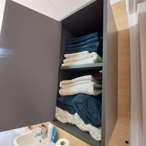 a bathroom with a closet with towels and a sink at Urban Penthouse in Patra