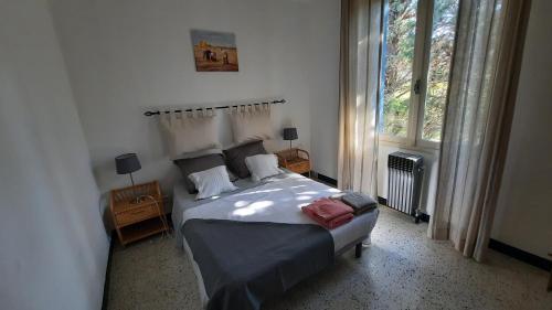 um quarto com uma cama e uma grande janela em A l'ombre de l'olivier em Orgon