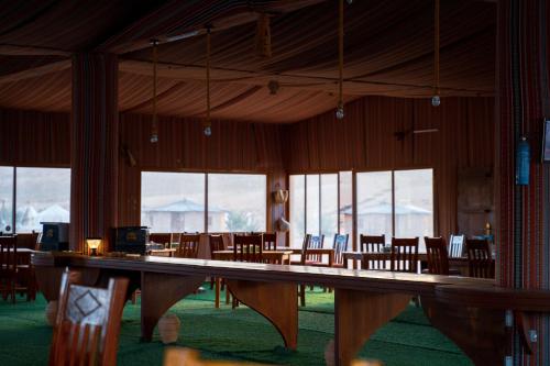a large room with tables and chairs and windows at Safari Desert Camp in Shāhiq