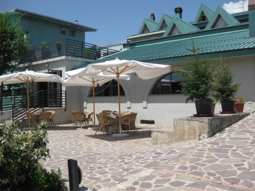 a patio with tables and umbrellas in front of a building at San Lorenzo Si Alberga in Camigliatello Silano
