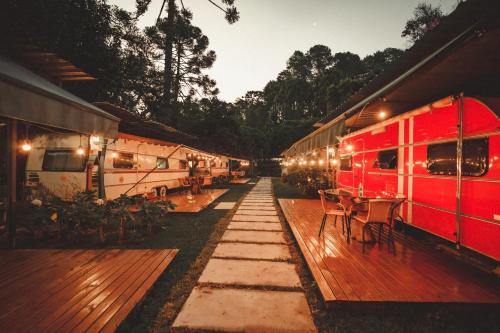 a row of trains parked next to a deck with tables at La Brume Trailers in Campos do Jordão