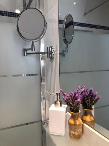 La salle de bains est pourvue d'un miroir et d'un lavabo avec des fleurs. dans l'établissement Quinta Quinze, à Boliqueime