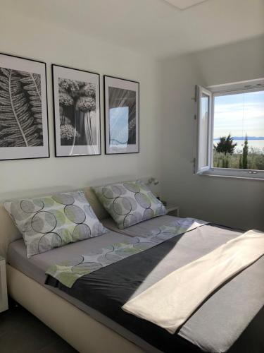 ein Schlafzimmer mit einem Bett mit vier Bildern an der Wand in der Unterkunft Apartments Villa Prima in Privlaka