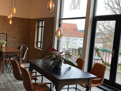 - une salle à manger avec une table, des chaises et des fenêtres dans l'établissement Atalanta-Wellness Roermond 'de Wethouder', à Herten
