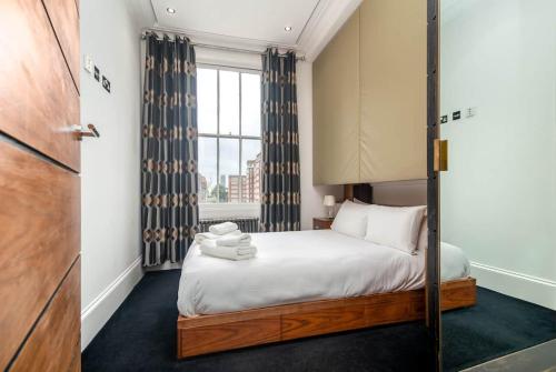 een kleine slaapkamer met een bed en een raam bij Award-winning designer apartment in Londen
