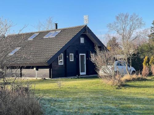 uma casa preta com um carro estacionado em frente em Hyggeligt og lyst feriehus nær stranden i Klint em Nykobing Sjaelland