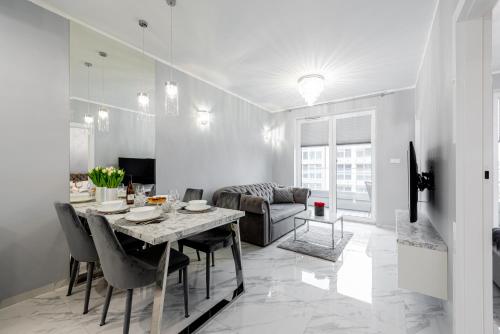 a dining room and living room with a table and chairs at Unique Baltic Apartments - Apartament z garażem in Kołobrzeg