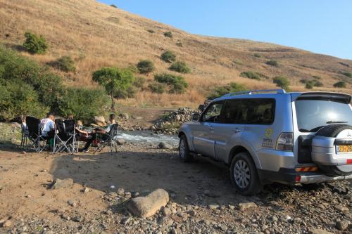 a van parked on a dirt road with people sitting in chairs at Helios Luxury Suites in Had Nes