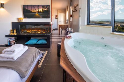 ein Badezimmer mit einer großen Badewanne und einem Kamin in der Unterkunft Yama Wine Spa and Suites in Zichron Ja’akow