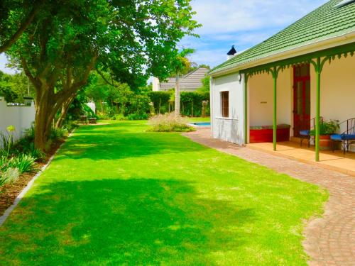 a yard with green grass and a house at Whistlewood Guesthouse Walmer, Port Eizabeth in Port Elizabeth