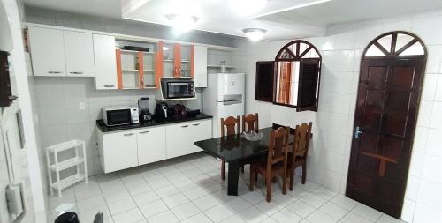 cocina con mesa, sillas y microondas en POUSADA VENTO NORTE CAMA & CAFÉ SUÍTES INDIVIDUAIs, en João Pessoa