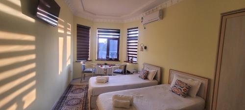 Zimmer mit 2 Betten, einem Tisch und einem Fenster in der Unterkunft Hotel Dilnura in Samarkand