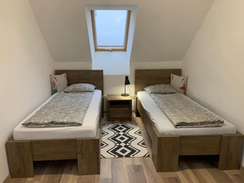 2 camas individuales en una habitación con ventana en Pirk Vendégház Vászoly en Vászoly