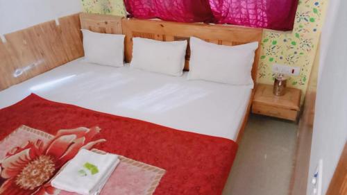 a bedroom with a white bed with a red blanket at Thakurji Palace in Jaisalmer