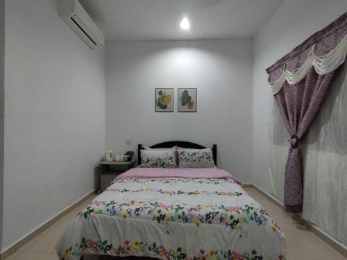 a bedroom with a bed with a pink comforter at Dahliya Roomstay Langkawi in Pantai Cenang
