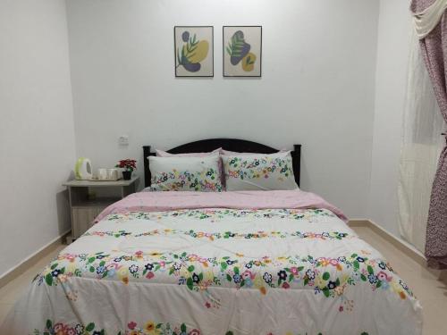 a bedroom with a bed with a floral bedspread at Dahliya Roomstay Langkawi in Pantai Cenang