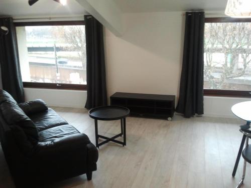 sala de estar con sofá y 2 ventanas en AppartsHotels'De Ville, en Bourg-lès-Valence