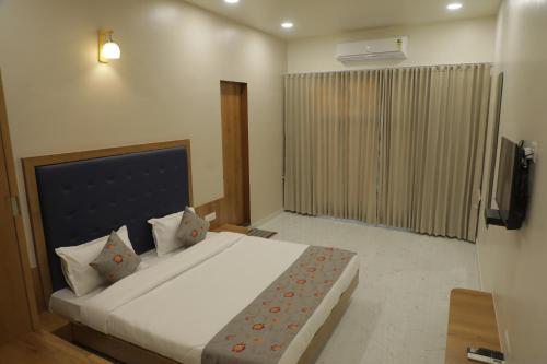 um quarto com uma grande cama branca e uma televisão em Hotel Panch em Kalol