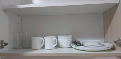 a shelf with white cups and plates on it at Condo Saga Davao City in Davao City