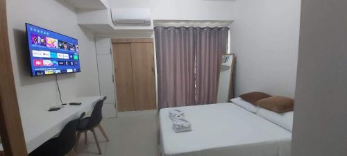 Habitación con cama, escritorio y TV. en Condo Saga Davao City en Dávao