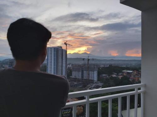 a man standing on a balcony looking at the sunset at Condo Saga Davao City in Davao City