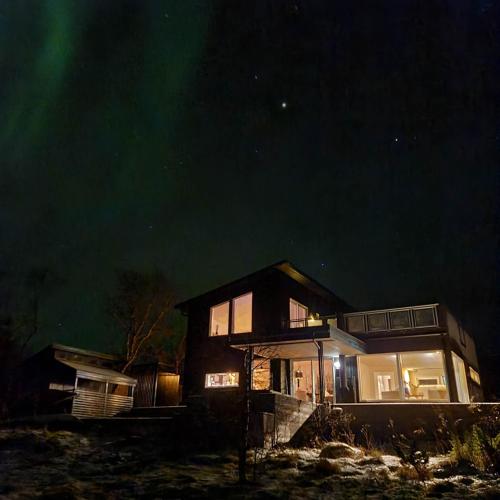 a house with the northern lights in the sky at Sand Beachhouse in Sand