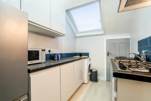 uma cozinha com armários brancos e uma janela em Deluxe 2-Bedroom Flat with Free parking em Birmingham