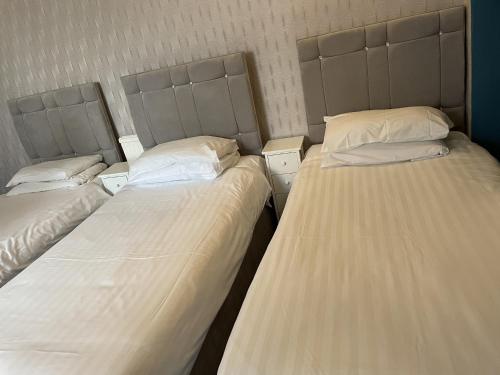 three beds in a room with white sheets and pillows at Diamonds Inn in York