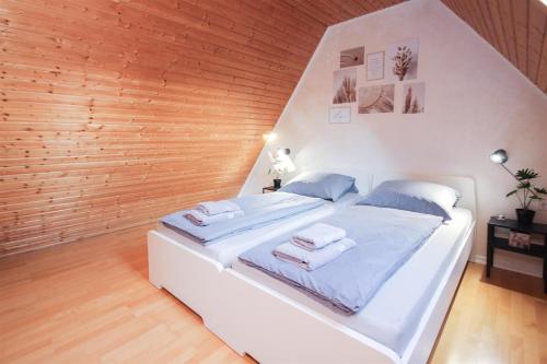 Cama blanca en habitación con pared de madera en ALFA Stuttgart 3Zi-Maisonette 6 Personen Zuffenhausen nahe Porsche & Bosch en Stuttgart