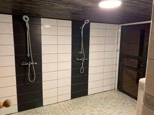 a shower in a bathroom with black and white tiles at Tonnila, big villa for 10-Person at Turku near Meyer gate in Turku