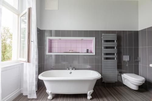 ein Badezimmer mit einer weißen Badewanne und einem WC in der Unterkunft Chateau de Didonne in Sémussac
