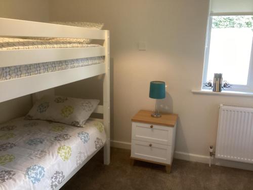 a bedroom with bunk beds and a table with a lamp at Forest Heath Holidays - Denphyl in Ringwood