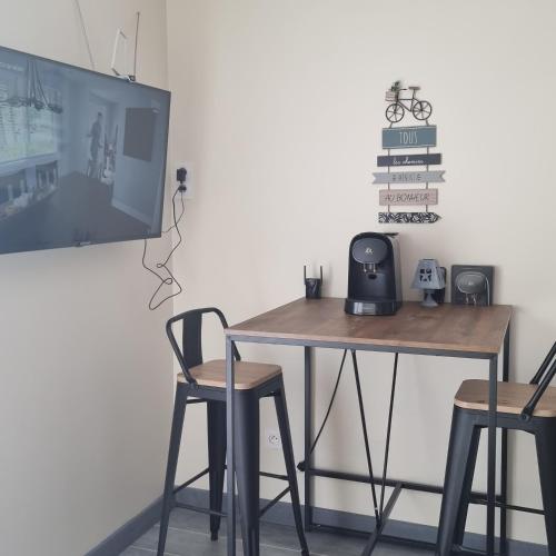 a table with two chairs and a tv on a wall at Chambre avec piscine partagée in Marcorignan