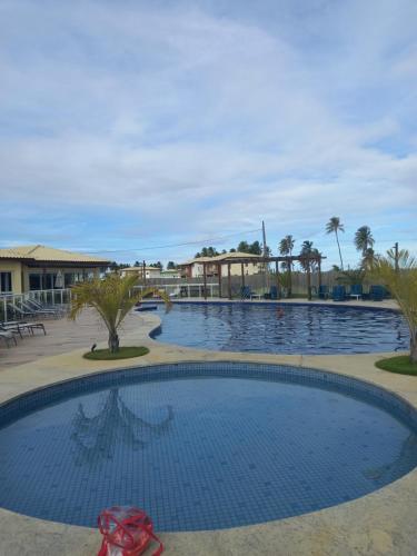 a large swimming pool in a resort with palm trees at Apto PDI na praia em Baixio in Baixio