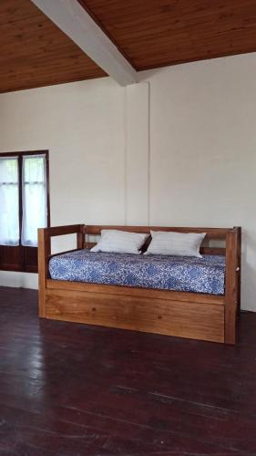Cama de madera en habitación con 2 ventanas en Miraflores Casa de Campo en San Salvador de Jujuy