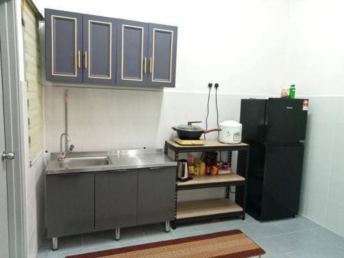 a kitchen with a sink and a black refrigerator at DAN'S Homestay Business Suite Home in Kota Tinggi