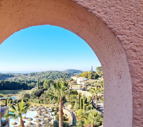 a view of a resort with palm trees and buildings at HAMEAU DES AMANDIERS - vue mer, golf et vignes in Saint-Cyr-sur-Mer