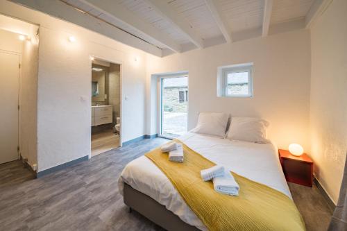 ein Schlafzimmer mit einem großen Bett mit Handtüchern darauf in der Unterkunft AR PENNITI - Magnifique maison en pierre proche plage in Landéda