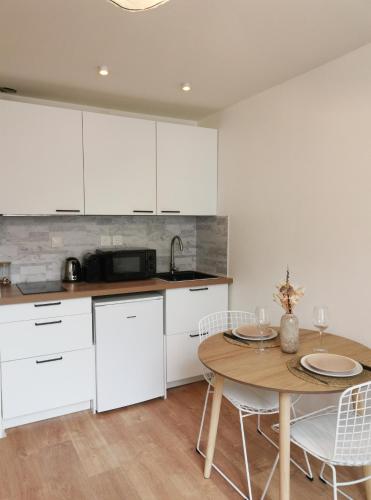 une cuisine avec des armoires blanches et une table avec des chaises dans l'établissement Appart Cozy - cœur historique de Moissac, à Moissac
